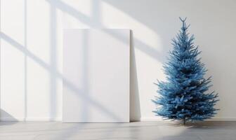 A blue Christmas tree sits in front of a white wall photo