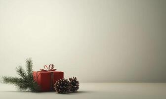 A red box with a ribbon sits on a table next to pine cones photo