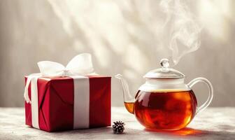 A red box with a white bow sits next to a teapot filled with steam photo