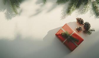 A red box with a ribbon sits on a table with pine cones photo