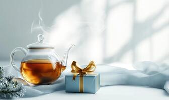 A tea kettle is sitting on a table next to a blue box with a gold ribbon photo