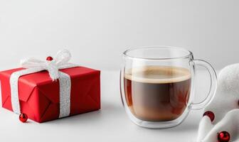 A red box with a white bow sits on a table next to a cup of coffee photo