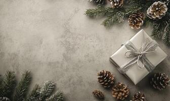 A white box with a silver ribbon sits on a table with pine cones and branches photo