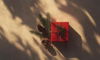 A red box with a green ribbon and pine cones on top of it photo