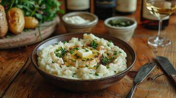 Cozy dinner table with a bowl of creamy mashed potatoes recipe topped with a pat of melting butter a sprinkle of chives and served alongside a plate of roasted chicken photo