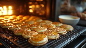 Oven a batch of fluffy buttermilk pancakes on a griddle and a bowl of buttermilk and syrup nearby photo
