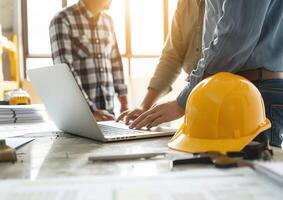 Architect collaborating with engineers around a laptop, discussing building construction plans photo