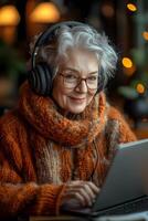 A senior woman enthusiastically attending a virtual class with wireless headphones and a laptop. Her modern, tech-friendly environment adds to the learning vibe. photo