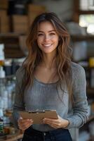 Smiling woman holding a clipboard in an e-commerce stockroom, surrounded by neatly arranged products. The organized space highlights her business success. photo