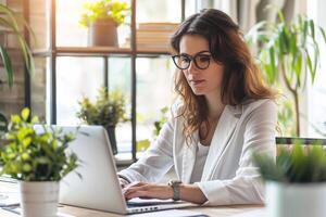 Business woman using a laptop to manage home insurance policies, professional attire, modern office environment photo