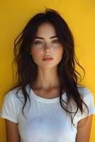 Top half body image of a young woman in a white t-shirt against a yellow blur backdrop, suited for clothing brand promotion. photo
