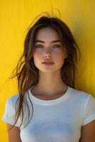 White t-shirt fashion portrait of a young woman with a yellow blurred background, focusing on the top half of her body. photo