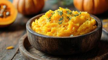 Steaming bowl of pumpkin puree garnished with thyme on rustic wooden table photo