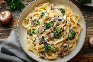 Tagliatelle pasta with creamy sauce, mushrooms, and broccoli served in a bowl photo