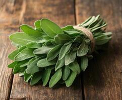 Fresh sage leaves tied together sitting on a rustic wooden table photo