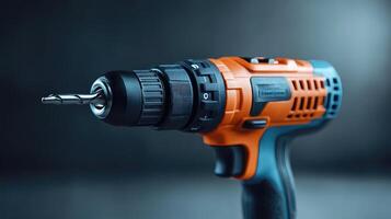 Orange and black cordless drill pointing left on blue background photo