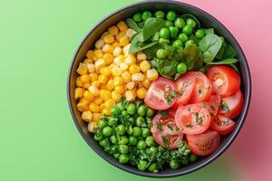 Fresh salad with spinach, tomatoes, corn and peas on green background photo