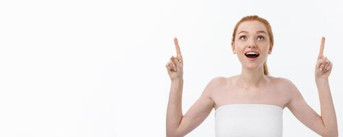 Portrait of young redhead female with perfect freckled skin showing something interesting at copy space wall for your advertising content. photo