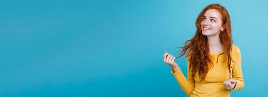 Portrait of happy ginger red hair girl with freckles smiling looking at camera. Pastel blue background. Copy Space photo