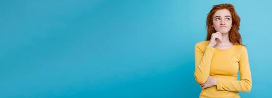 Portrait of happy ginger red hair girl with freckles smiling looking at camera. Pastel blue background. Copy Space photo