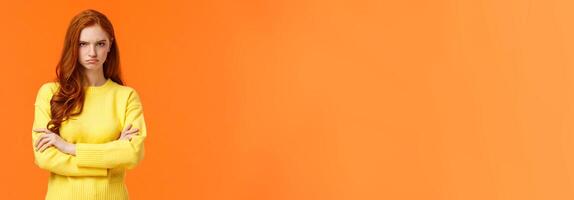 I am mad. Offended sulky cute and timid redhead curly girl, cross arms chest, sulking angry and tensed, frowning stare disappointed someone sad rude words, standing orange background insulted photo