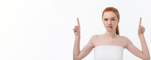 Portrait of young redhead female with perfect freckled skin showing something interesting at copy space wall for your advertising content. photo