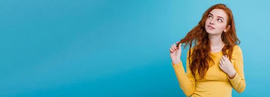 Portrait of happy ginger red hair girl with freckles smiling looking at camera. Pastel blue background. Copy Space photo