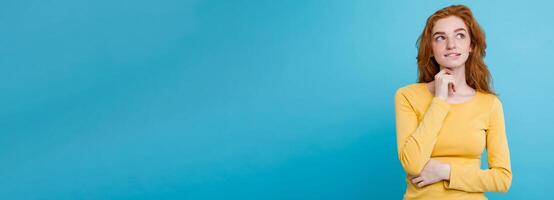 Portrait of happy ginger red hair girl with freckles smiling looking at camera. Pastel blue background. Copy Space photo