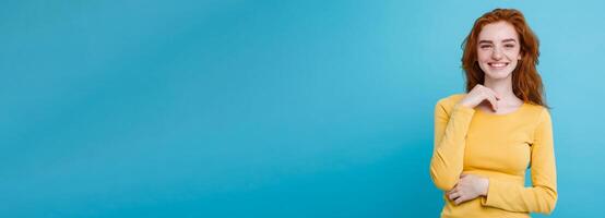 Portrait of happy ginger red hair girl with freckles smiling looking at camera. Pastel blue background. Copy Space photo