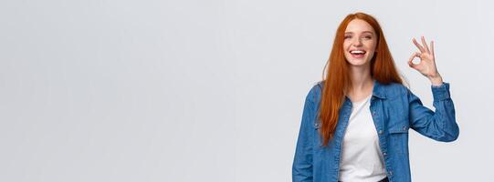 Waist-up portrait charismatic redhead woman having fantastic time with friends on party showing okay gesture, like or approve product, good service, laughing and smiling, white background photo