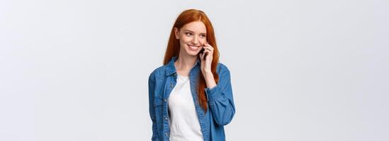 Girl calling boyfriend pick her up after classes. Attractive outgoing redhead woman talking on phone, smiling carefree, look away as having casual conversation on smartphone, white background photo