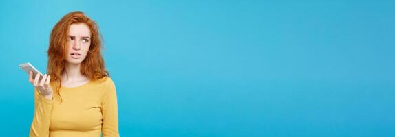 Lifestyle and Technology concept - Portrait of cheerful happy ginger red hair girl with joyful and exciting smiling to camera. Isolated on Blue Pastel Background. Copy space. photo