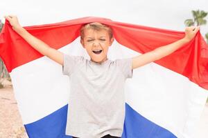 happy, cheerful boy holding the flag of the Netherlands photo