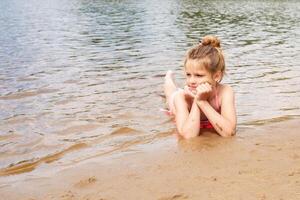 close-up portrait happy girls on the beach during summer holidays. girl lies on the beach and joyfully looks at the water photo