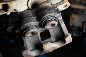 Old caliper brake piston has oil stains and the rubber is torn. The car brake system needs repair photo