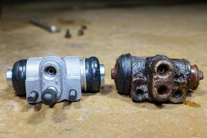 New and old car brake slave cylinder.The mechanic is repairing the car brake system.Old car parts on the table in the workshop. Selective focus. photo