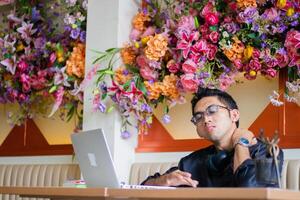 handsome asian male student his shoulders are sore from tiredness doing assignments in front of laptop computer on the table, sitting in a cafe where he works. health, education, technology, lifestyle photo