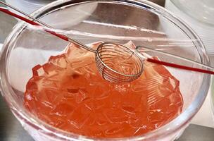Sweet and delicious orange agar-agar jelly dessert toppings in glass bowl with plastic cover and spoon isolated on horizontal ratio background. photo