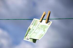 hundred euro paper bills are pinned to a string with clothespins photo