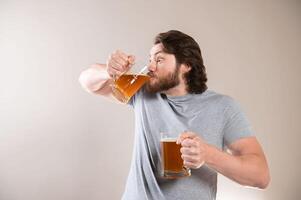 Young man drinking beer isolated on gray studio background, excited expression photo