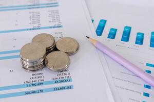 Close up view of stack of coins and pencil on top of financial data paperwork photo