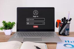 A laptop computer on the desk with a login page on the screen. photo