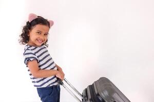 A happy little Asian girl posing with wear headband while pulling a suitcase photo