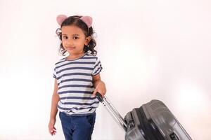 A cheerful little Asian girl posing with a suitcase. Travel or holiday concept. photo