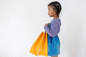 Side view of a little Asian girl holding yellow paper shopping bag photo