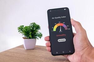 Man in room checking air quality index using a smartphone photo