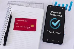 Office desk with credit card and smartphone with successful payment message on smartphone screen photo