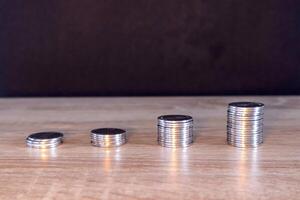 Stack of coins on wooden table with dark background. Sorted by level. photo