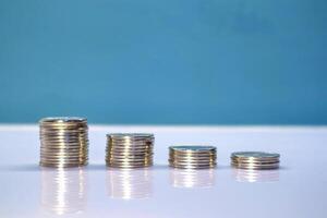 Stack of coins on white table with blue background. Sorted by level. photo