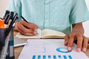 Man writes a summary of the analysis of a job report in a notebook photo